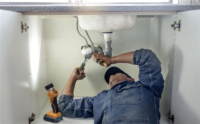 Plumber repairing pipes beneath a bathroom sink in Springfield