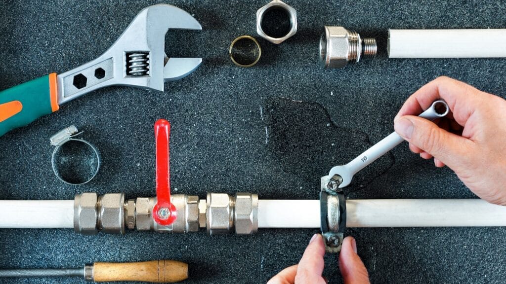 Plumber repairing a pipe valve with an adjustable wrench in Springfield