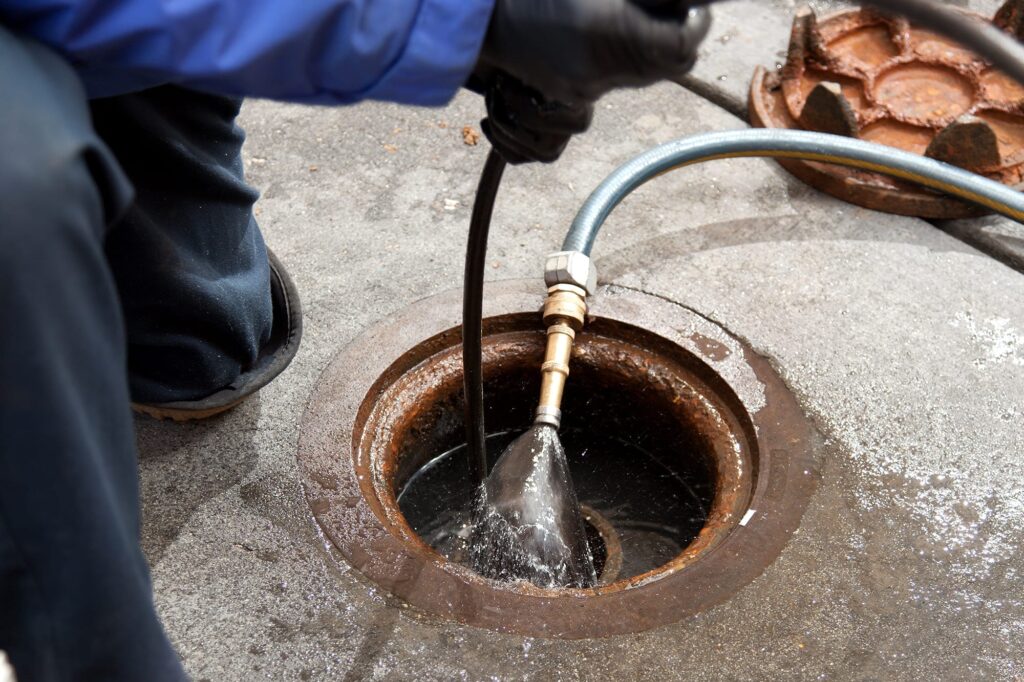 Plumber hydro jetting a sewer line through a manhole in Springfield