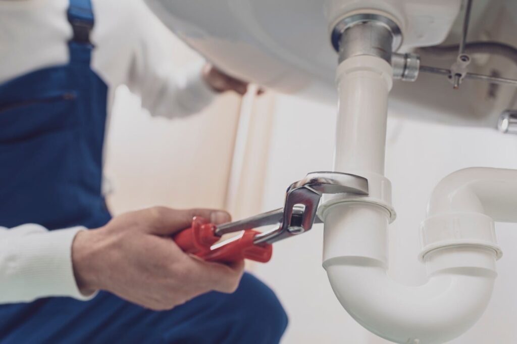 Plumber repairing a white drain pipe beneath a sink in Springfield