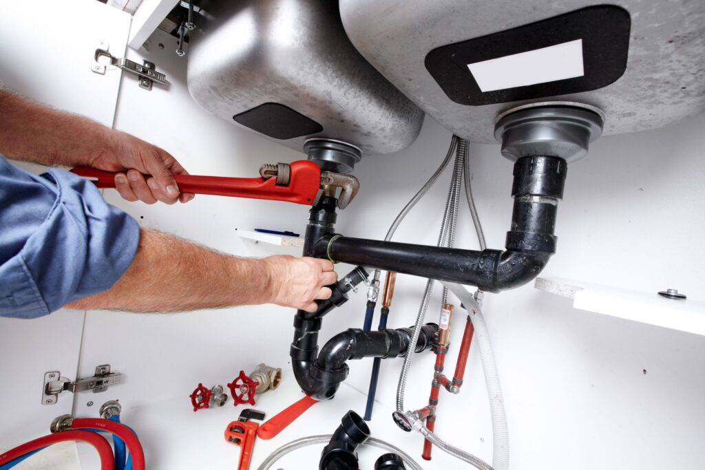 Plumber repairing drain pipes beneath a kitchen sink in Springfield