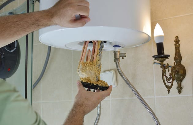 Technician removing mineral buildup from a water heater in Springfield