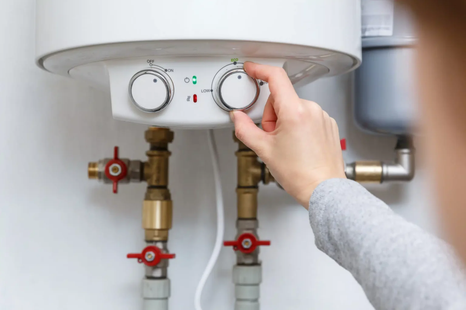 Homeowner adjusting the temperature controls on a water heater in Springfield